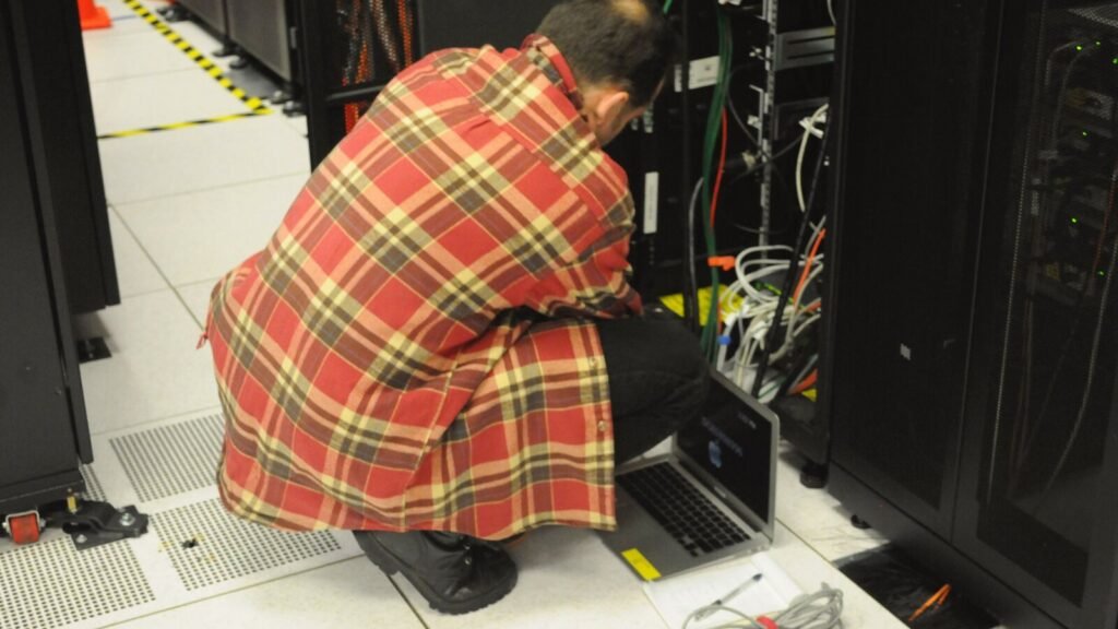 Technician with a laptop working on a server rack in a data centre