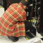 Technician with a laptop working on a server rack in a data centre